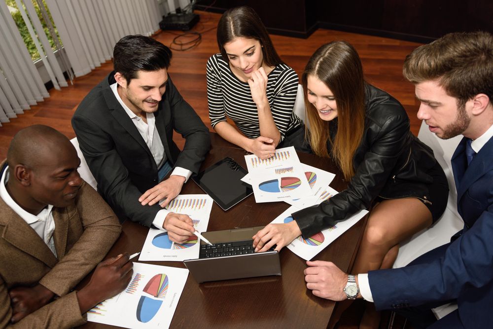 Business colleagues working on a problem together with charts and graphs