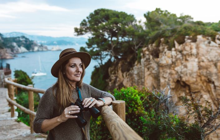 Woman with binocular on coastal walkway