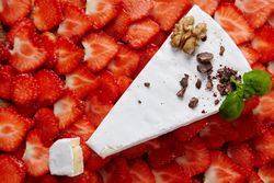 Large slice of cheese on a bed of sliced strawberries