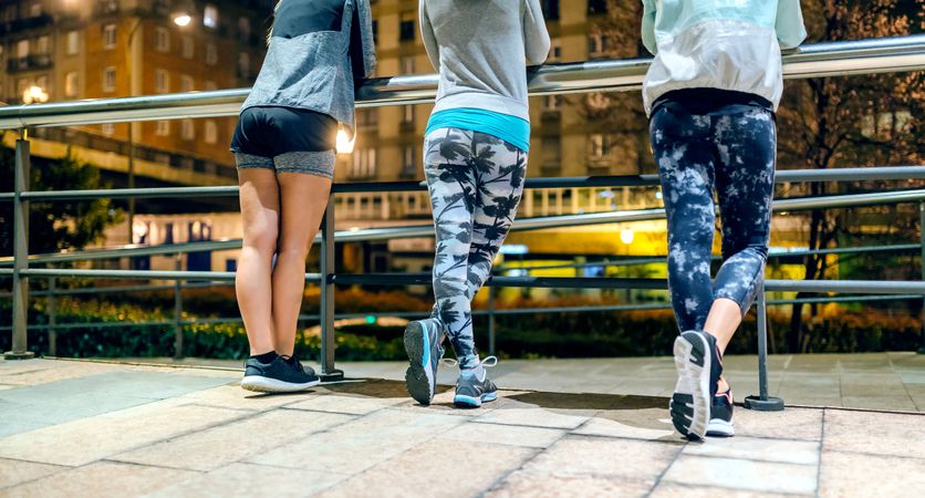 Legs of female runners resting after training at night on town