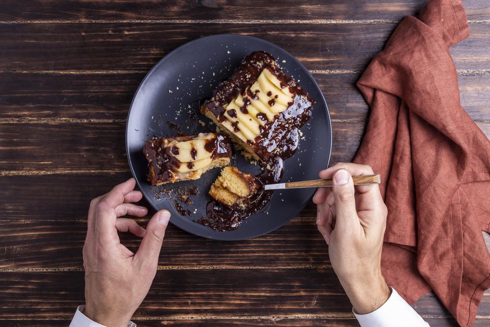Person taking a bite of cake with fork from plate on table