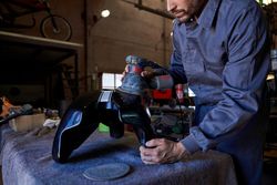 Crop mechanic repairing car in dark garage