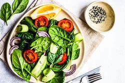 Leafy spinach salad with lemon slice served with sesame seeds