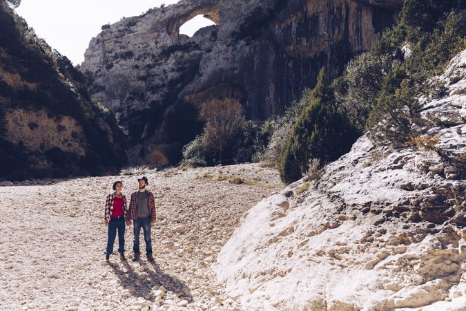 Woman and man standing on stones between high hills