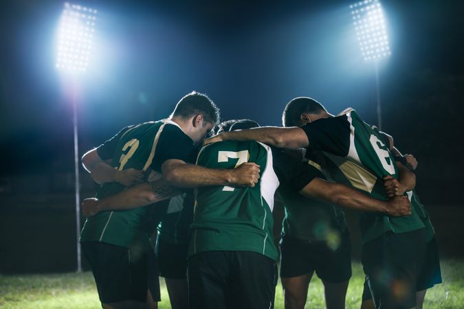 Rugby players standing together after the game under lights