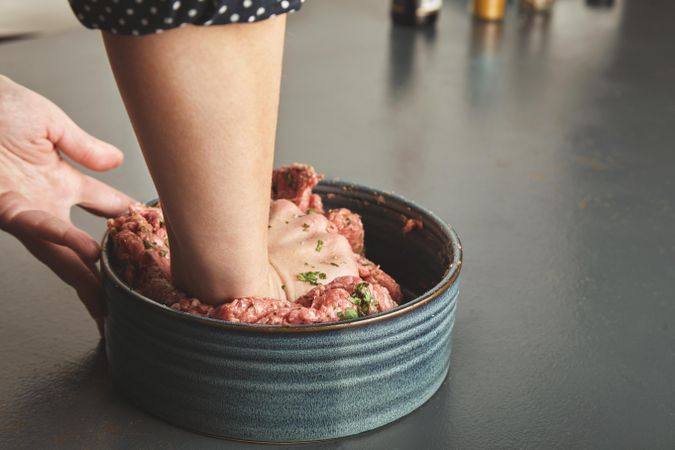 Woman’s hands mixing ground beef with herbs and spices