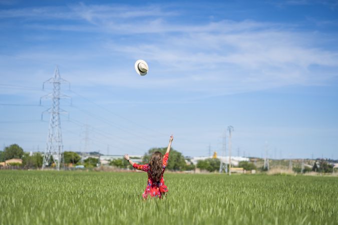 Young woman throwing up hat in field