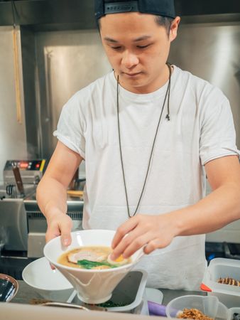 Young male decorating prepared Japanese dish