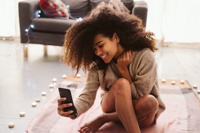 Black woman taking selfie on floor