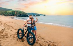 Male and female taking picture with phone standing with bicycle