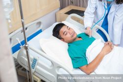 Physician treating sick man in hospital bed bGZZe4
