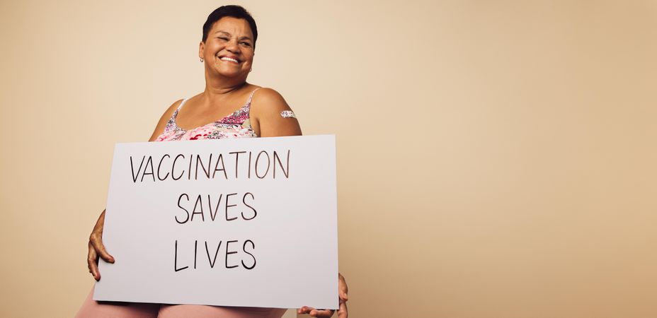 Older woman holding a banner with "vaccination saves lives" slogan
