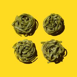 Green bird's nest pasta organized over yellow background