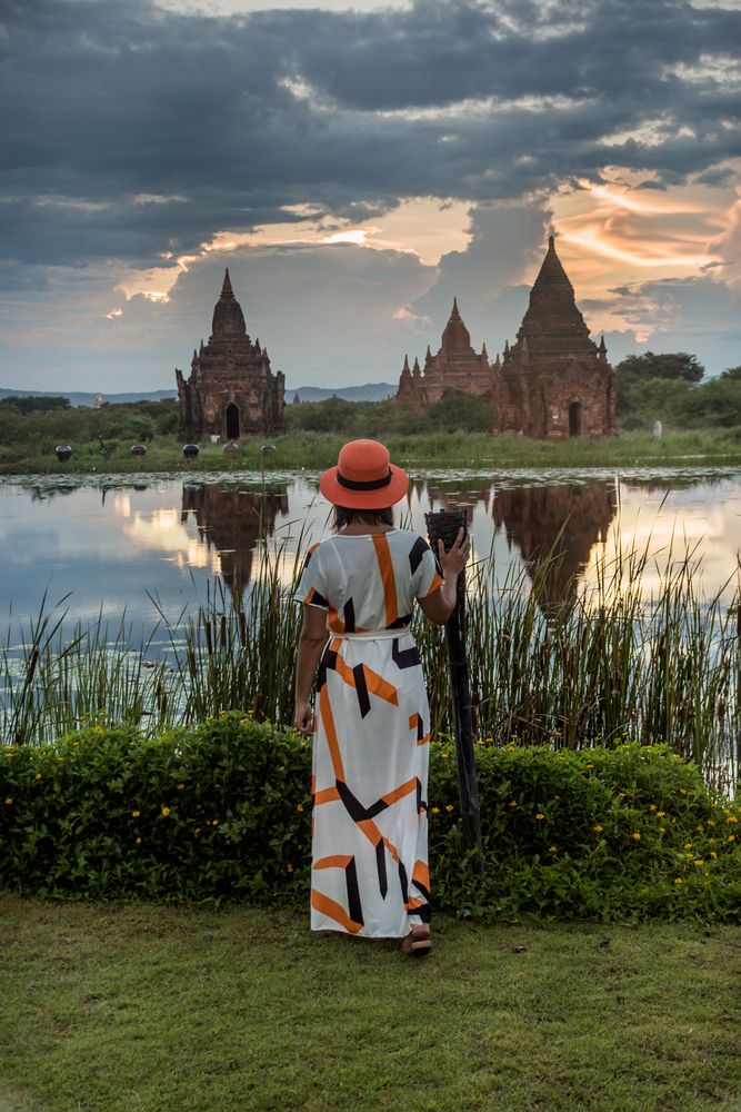 Woman standing at lakeside and enjoying view of Buddhist temples