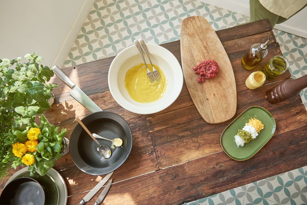Various ingredients for preparing steak tartare placed on wooden