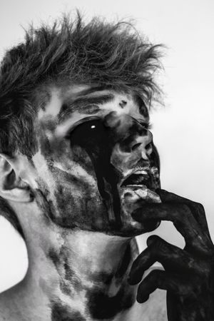 Grayscale portrait of young man with dark face paint