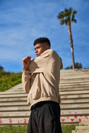 Serious Hispanic sportsman stretching arms on street