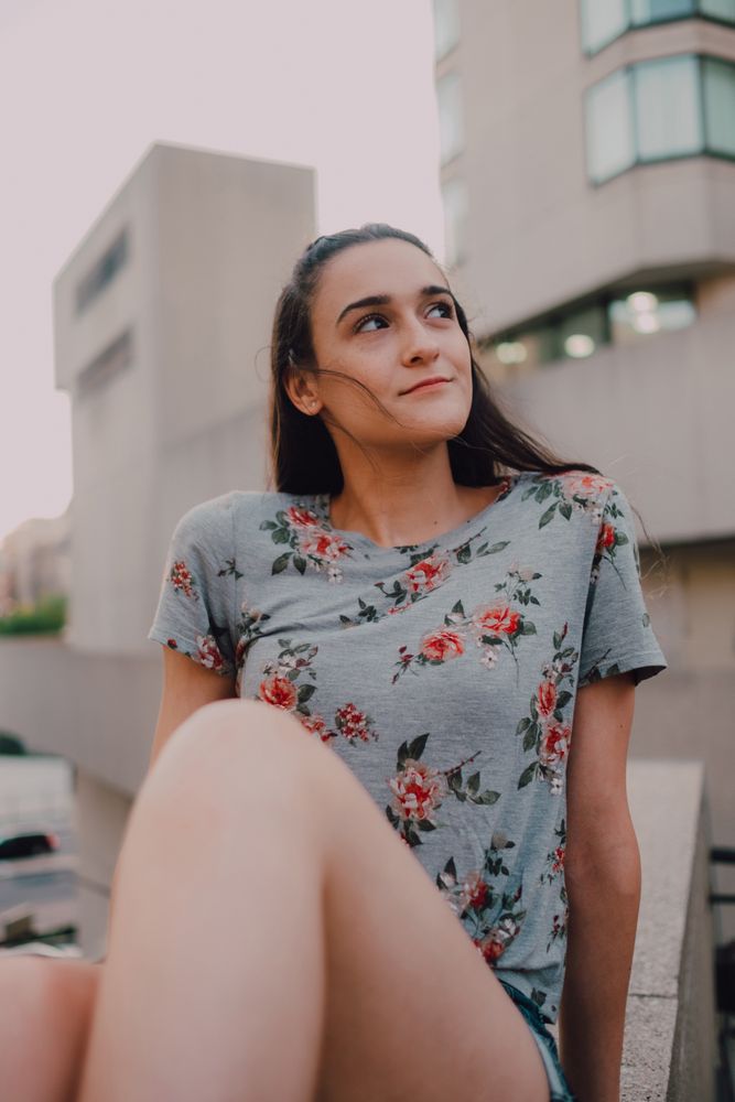 Smiling modern woman sitting on parapet