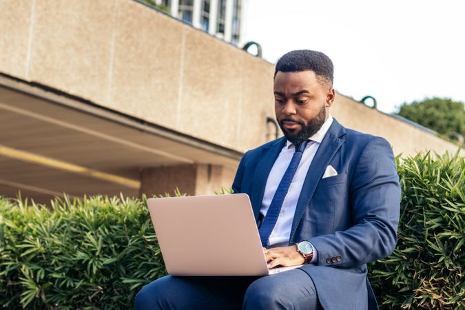 Black business man in suit working with laptop outside