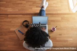 Overhead shot of woman sitting on wooden floor and working on laptop with healthy smoothie 41NvDb