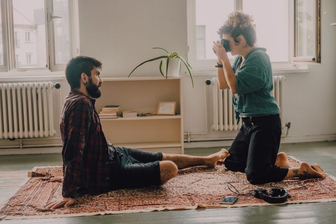 Woman photographing boyfriend on camera while resting at home