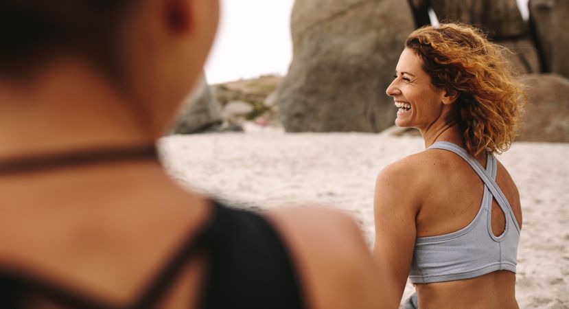 Women practicing yoga sitting on beach