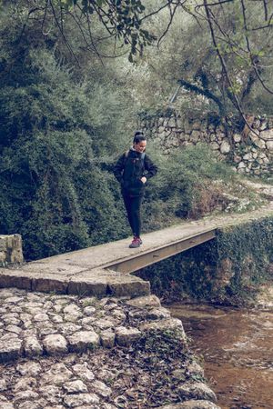 Hiker contemplating river on bridge in nature