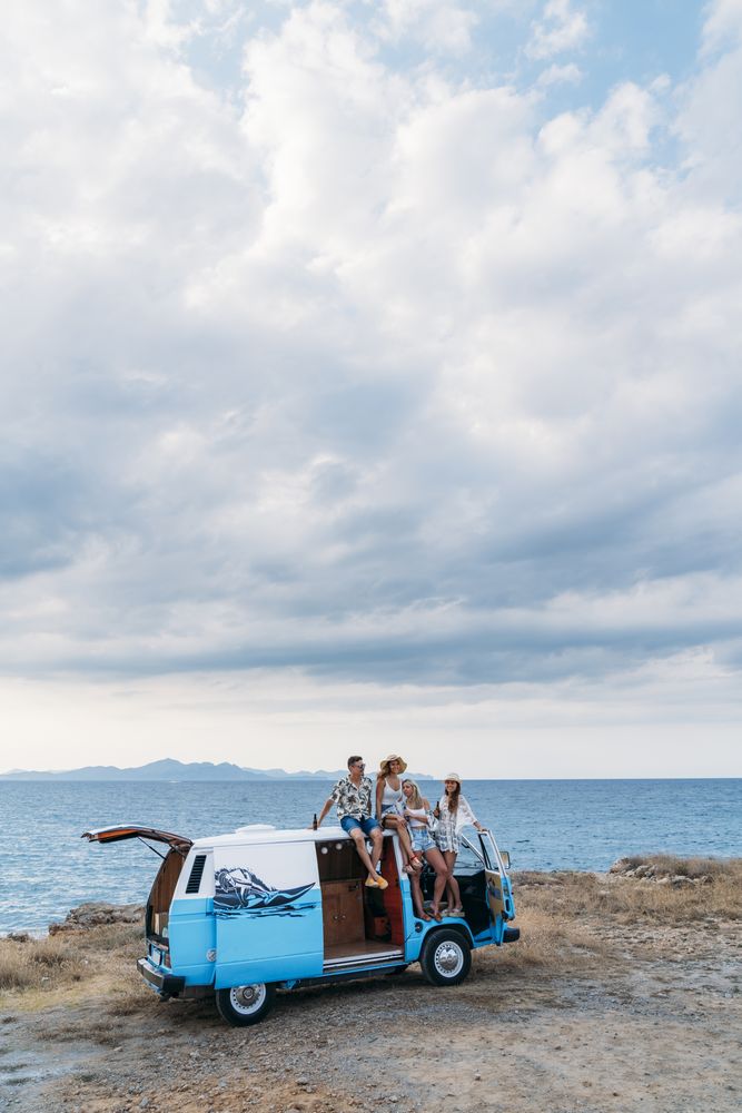 Relaxed friends comfortable placing on top of blue car