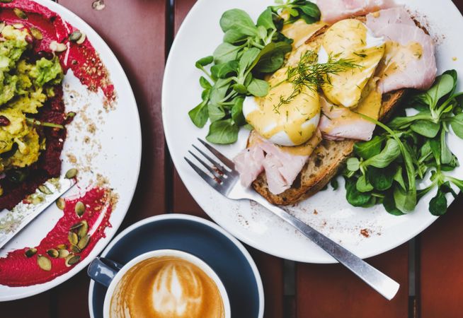 Eggs Benedict with greens, coffee, side dish, top view