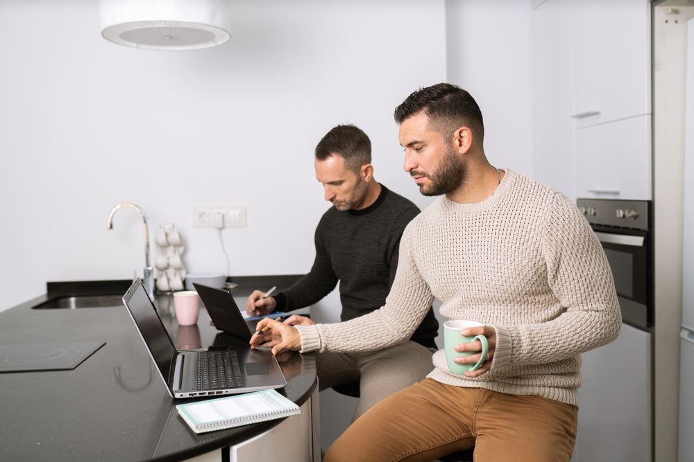 Two men working from their kitchen counter