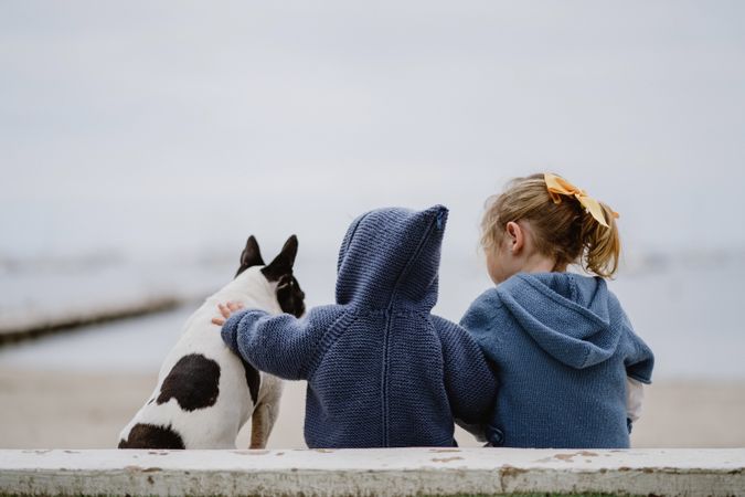 Kids hugging dog on beach