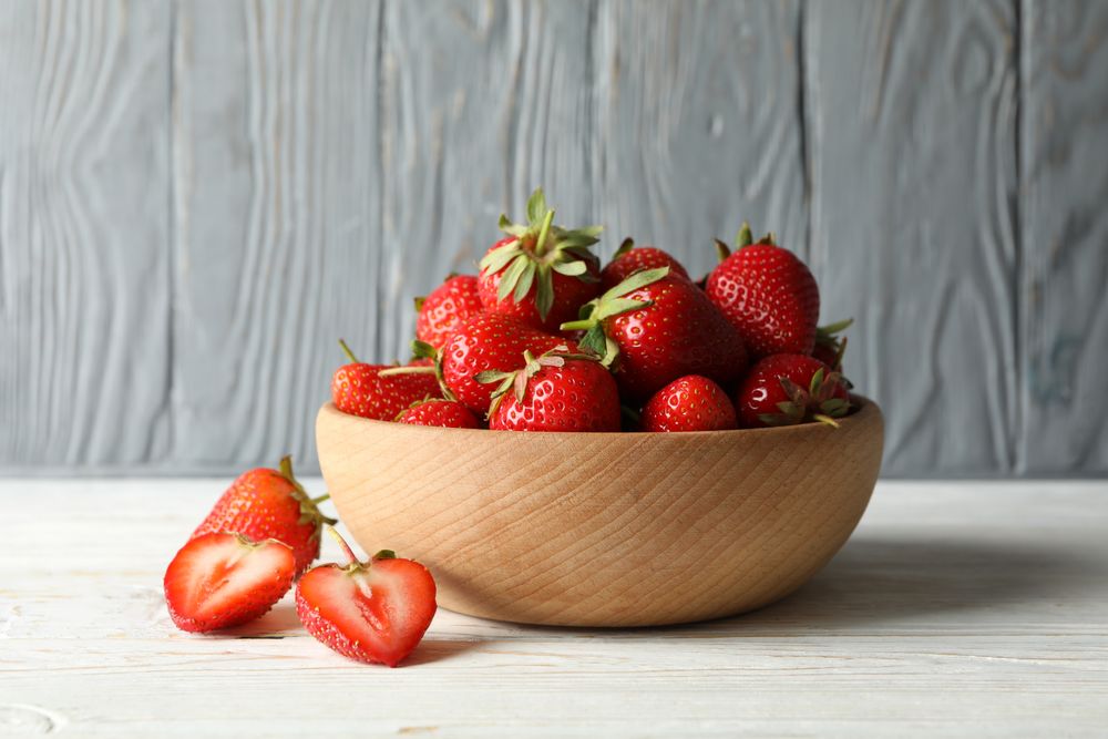 Bowl with tasty strawberry on wooden table. Summer berry