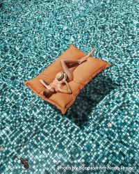 Woman on inflatable mattress in swimming pool 4AABq4