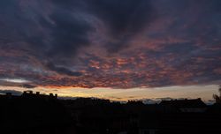 Dark clouds over the last light of sky before sunset over a French homes