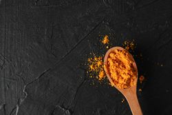 Looking down at wooden spoon of colorful turmeric, copy space