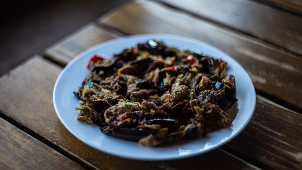 Plate of traditional Georgian eggplant dish with vegetable served on a cafe table