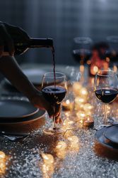 Hand holding wine bottle pouring into wine glass