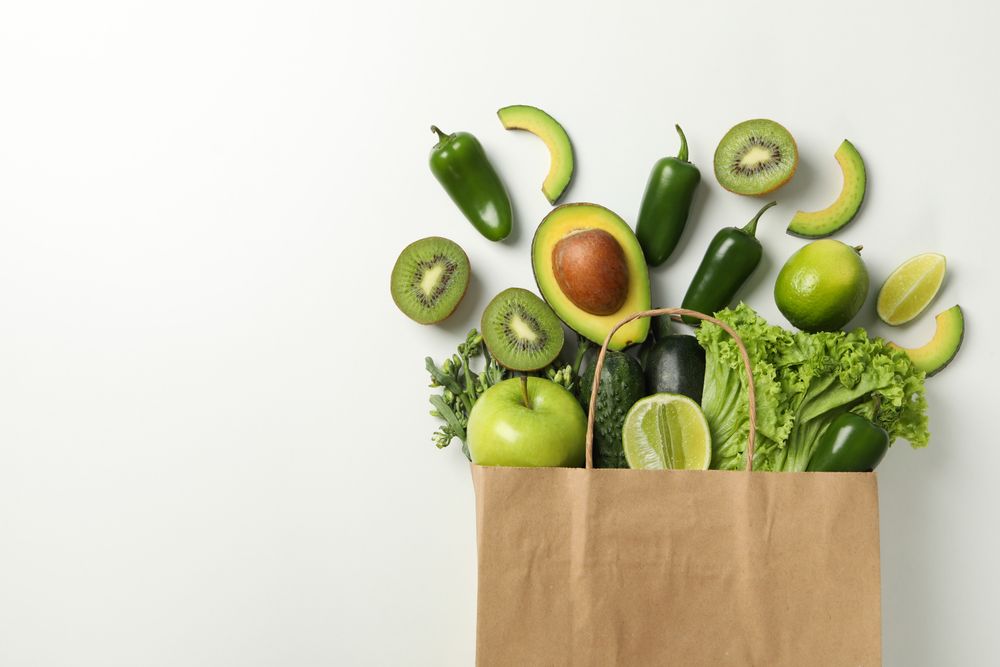 Paper bag with vegetables and fruits on blank background