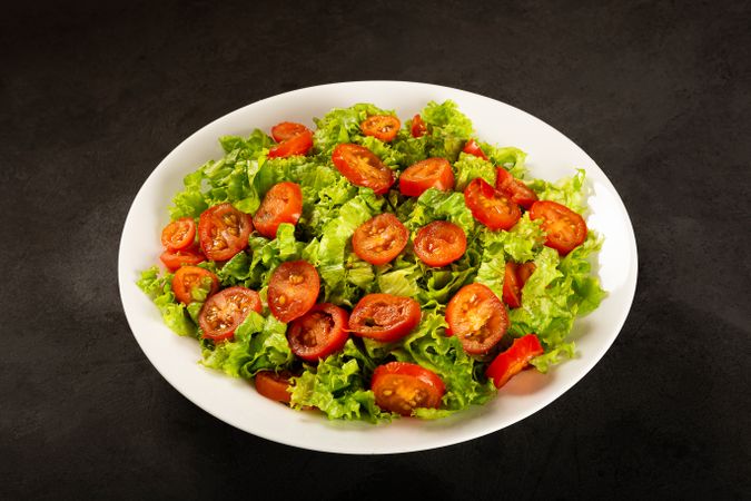 Bowl of sliced tomatoes on bed of lettuce
