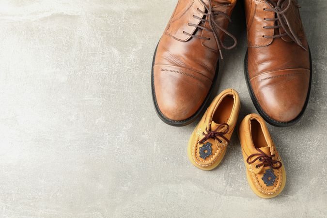 Brown leather shoes and children's shoes on grey background, space for text and top view