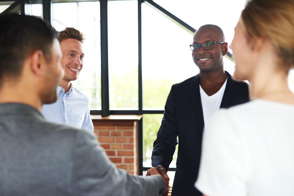 Two men shaking hands in a group of businesspeople