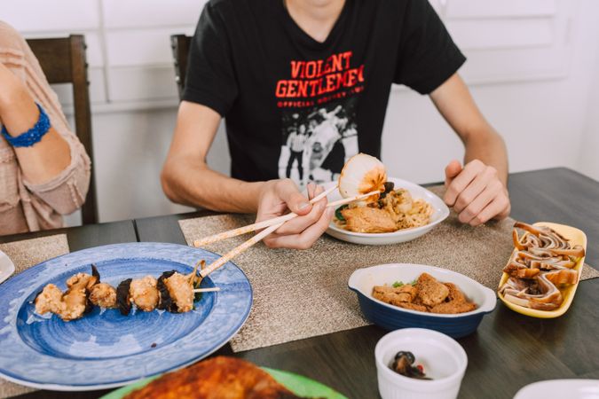 Cropped image of young man eating with chopsticks