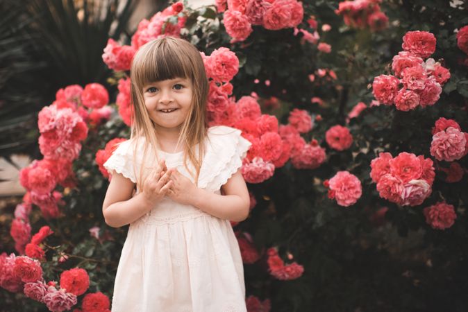 Girl in light dress standing near red flowers