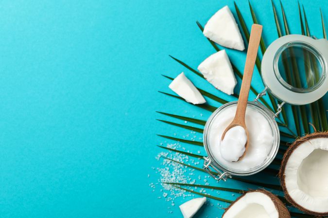 Coconut, palm branch and cosmetic on turquoise background. Tropical fruit