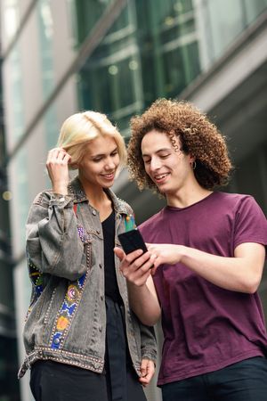Male and female looking down at cell phones walking on British city street