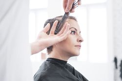 Hairdresser cuts woman's hair with scissors