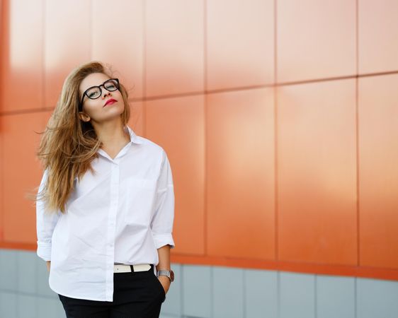 Woman in glasses in front of orange wall
