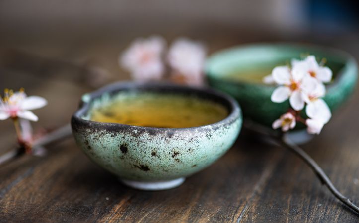 Asian style green tea set and blooming peach tree branch on wooden table