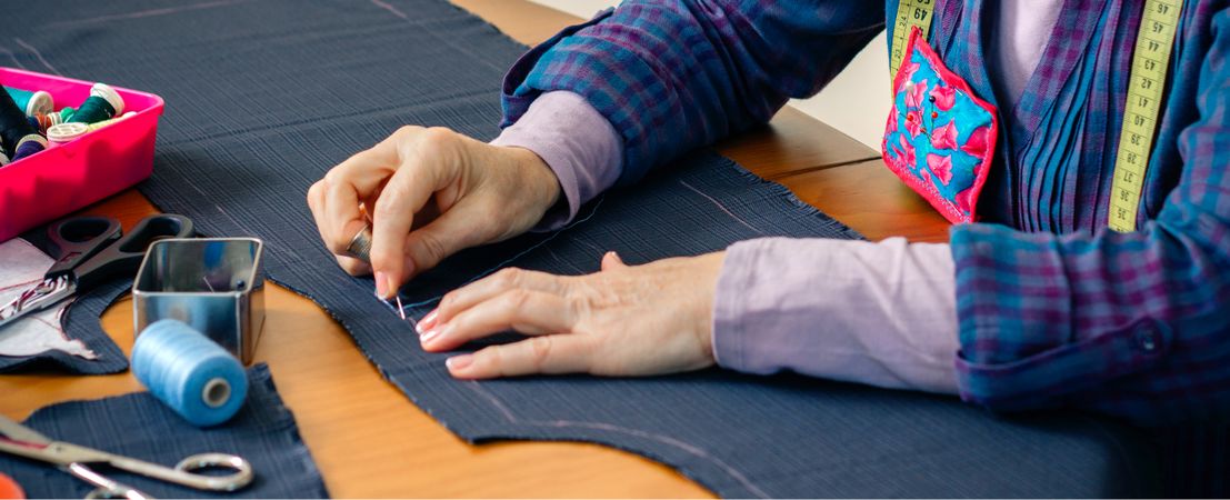 Mature female seamstress sewing cloth