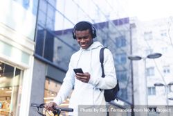 Young Black man biking in the street and checking his phone bxA3rd